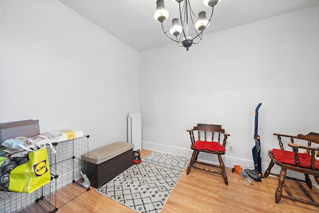 misc room featuring radiator, a notable chandelier, baseboards, and wood finished floors