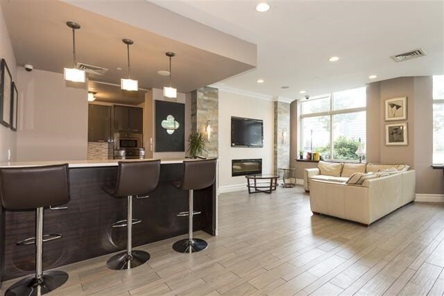 bar with visible vents, pendant lighting, ornamental molding, baseboards, and light wood-style flooring