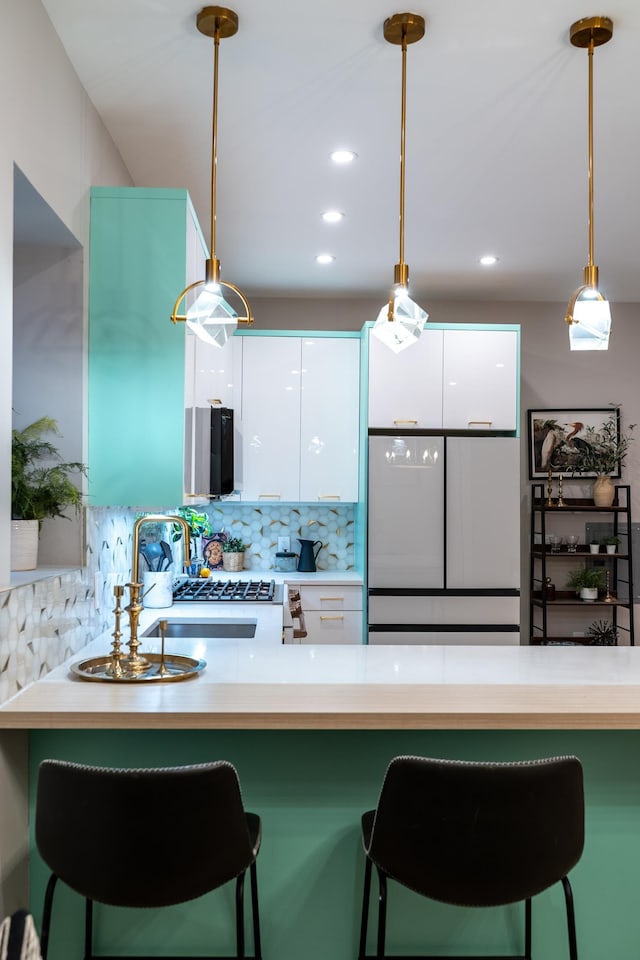 kitchen featuring pendant lighting, a kitchen breakfast bar, a sink, and freestanding refrigerator