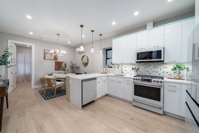 kitchen featuring gas range oven, white microwave, white cabinetry, dishwasher, and a peninsula