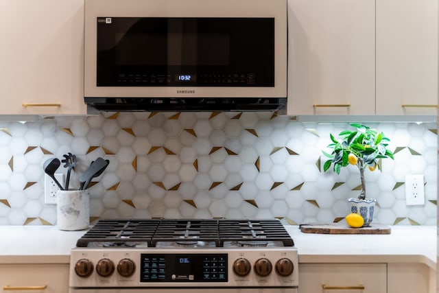 details featuring stainless steel gas range, white cabinets, light countertops, and backsplash