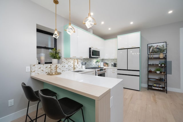 kitchen with a peninsula, white appliances, a sink, light countertops, and tasteful backsplash