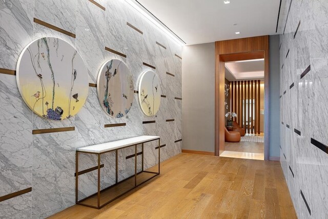 hall featuring light wood-type flooring and tile walls