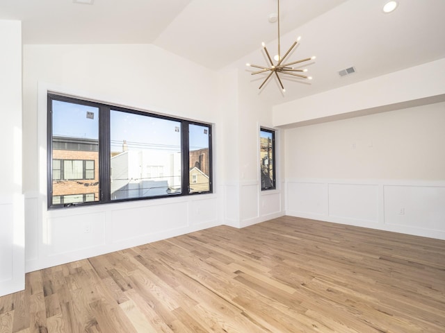 unfurnished room featuring a chandelier, light hardwood / wood-style flooring, and vaulted ceiling