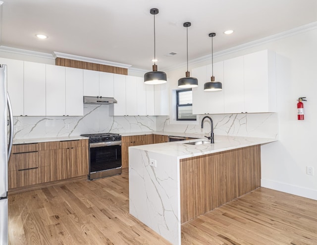 kitchen featuring white cabinets, stainless steel gas range oven, light stone countertops, and sink