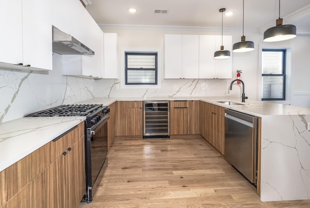 kitchen with wall chimney range hood, wine cooler, stainless steel dishwasher, decorative light fixtures, and white cabinets