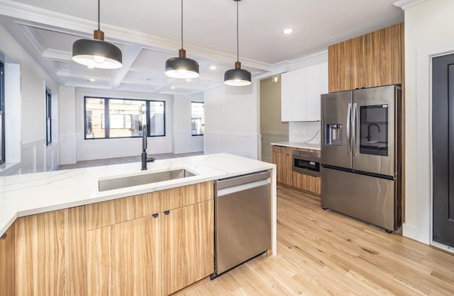 kitchen featuring hanging light fixtures, sink, white cabinets, and stainless steel appliances