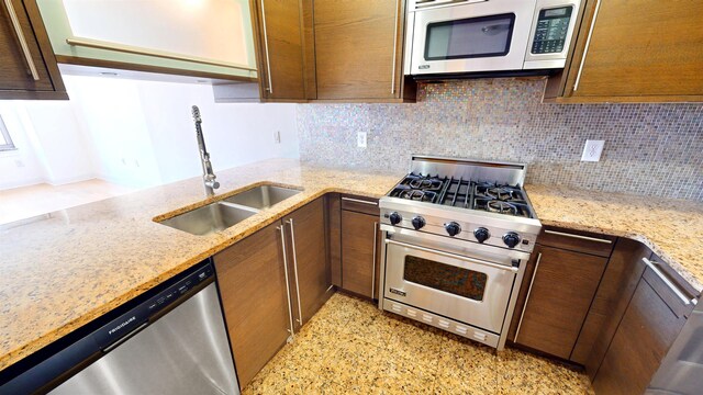kitchen featuring a sink, light stone counters, tasteful backsplash, and stainless steel appliances