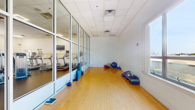 exercise room with a healthy amount of sunlight, wood finished floors, and visible vents