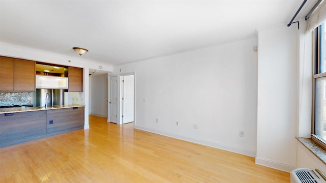 unfurnished living room with light wood-style floors, baseboards, plenty of natural light, and a sink