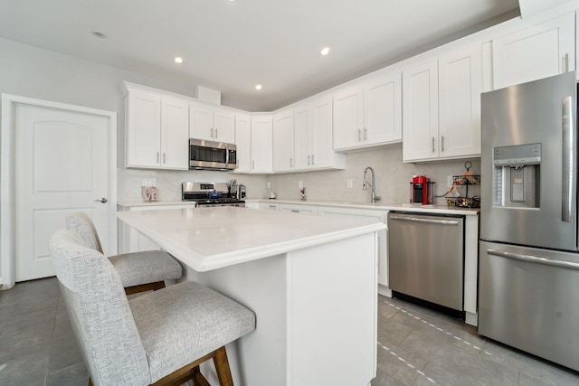 kitchen featuring a kitchen bar, white cabinets, backsplash, and stainless steel appliances