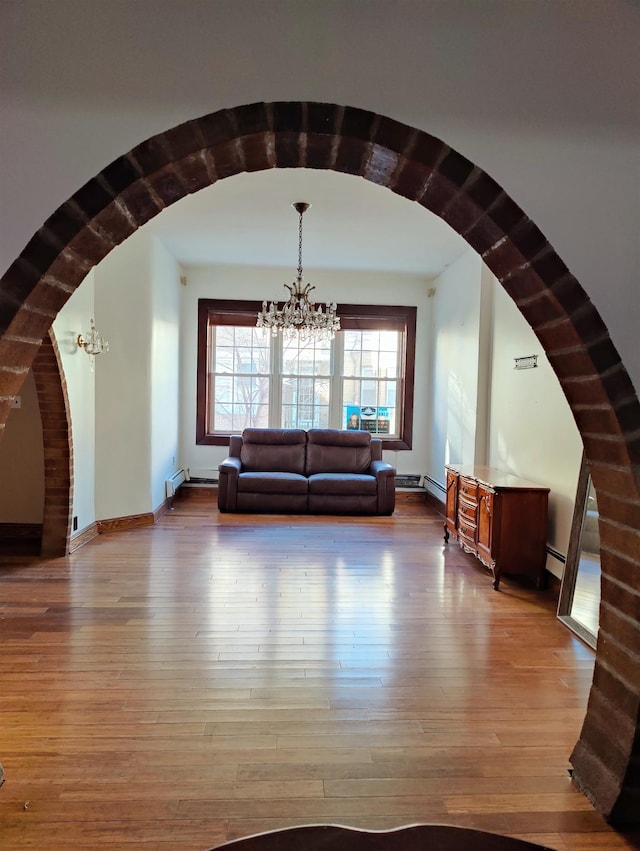 interior space with wood-type flooring, a chandelier, and baseboard heating