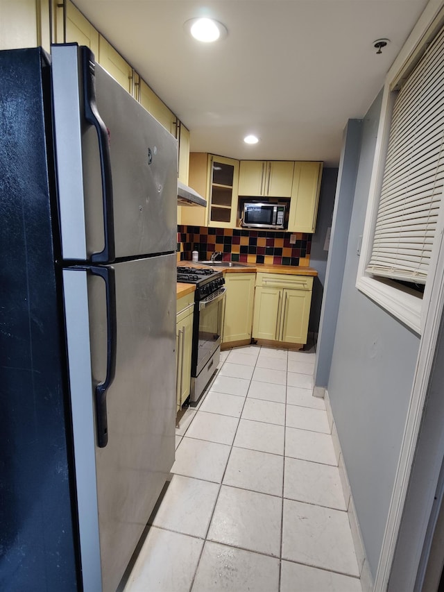 kitchen featuring butcher block countertops, light tile patterned floors, sink, appliances with stainless steel finishes, and backsplash