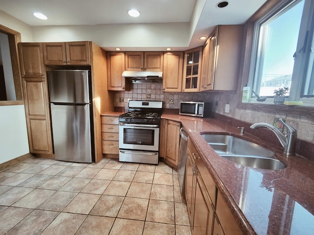 kitchen featuring sink, dark stone countertops, light tile patterned floors, appliances with stainless steel finishes, and backsplash