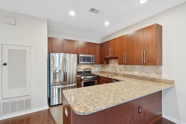 kitchen featuring appliances with stainless steel finishes, sink, light stone counters, kitchen peninsula, and decorative backsplash