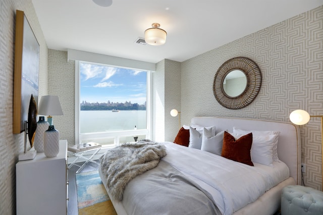 bedroom with wallpapered walls and a water view