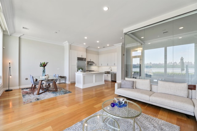 living area with ornamental molding, light wood finished floors, baseboards, and recessed lighting