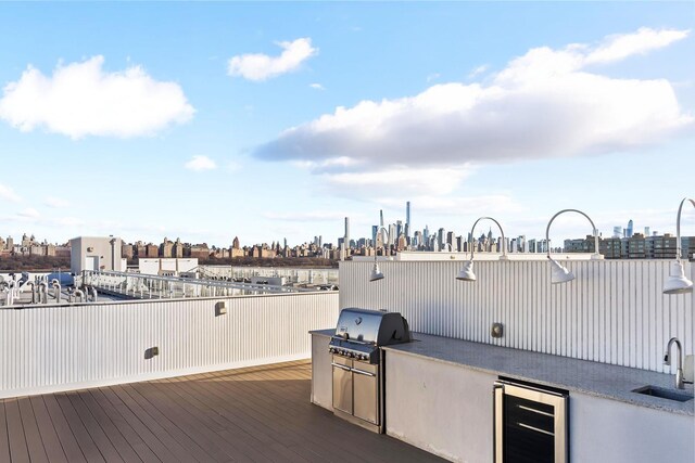 view of patio featuring beverage cooler, exterior kitchen, area for grilling, a sink, and a skyline view