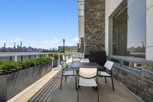 balcony with a view of skyline, outdoor dining area, and a patio area