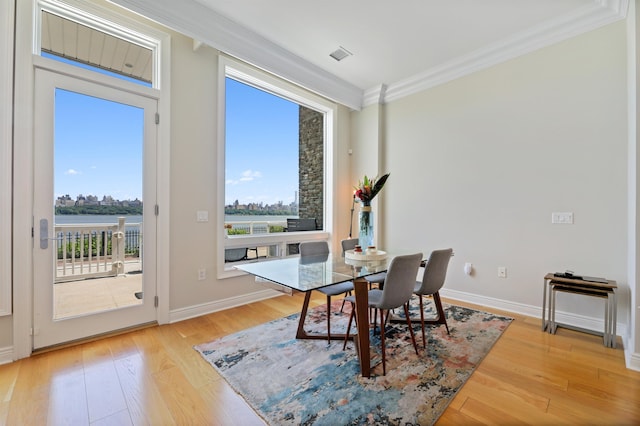 dining space featuring ornamental molding, light wood-style floors, and baseboards