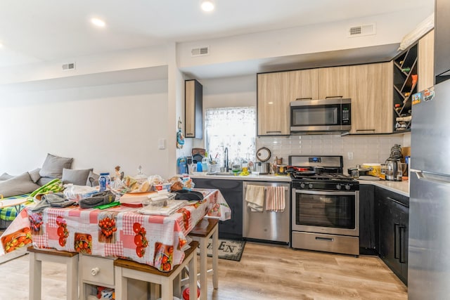 kitchen with sink, decorative backsplash, light wood-type flooring, light brown cabinetry, and appliances with stainless steel finishes