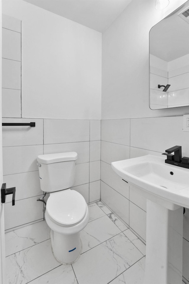 bathroom featuring toilet and tile walls