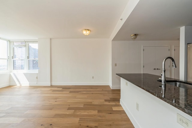 88 Morgan St Unit 2601, Jersey City, NJ 07302 - kitchen featuring a sink, baseboards, light wood finished floors, and dark stone counters