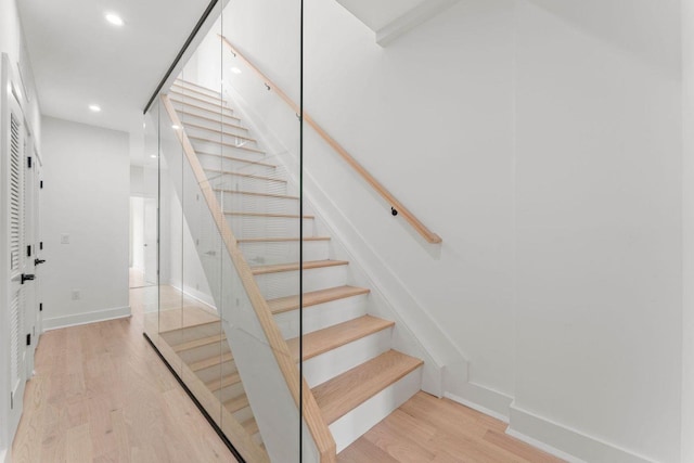 stairs featuring baseboards, wood finished floors, and recessed lighting