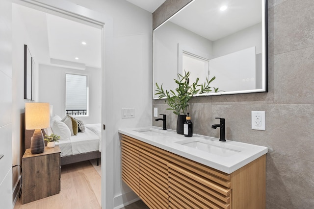 full bath with double vanity, a sink, backsplash, and ensuite bathroom