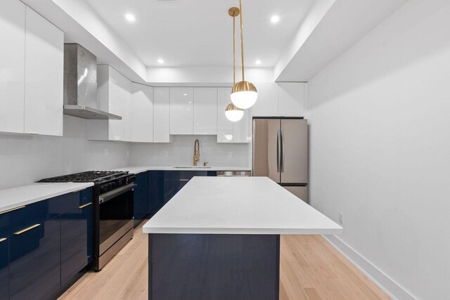 kitchen featuring wall chimney range hood, freestanding refrigerator, a center island, modern cabinets, and gas range