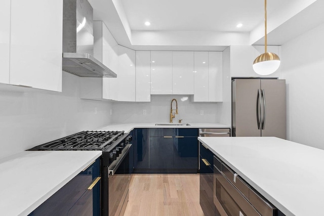 kitchen with freestanding refrigerator, white cabinetry, black range with gas cooktop, modern cabinets, and wall chimney exhaust hood