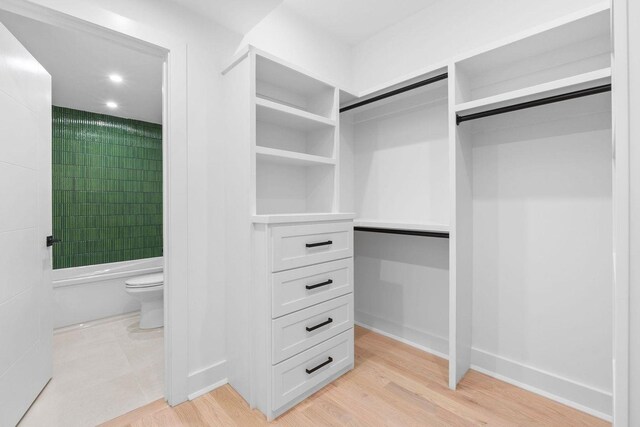 walk in closet with light wood finished floors