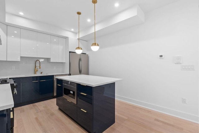 kitchen featuring white cabinetry, stainless steel appliances, a sink, and light countertops