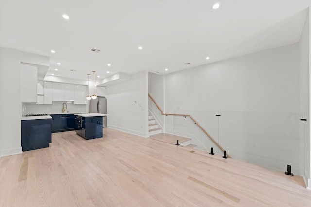 kitchen with light wood-style floors, white cabinets, light countertops, a center island, and decorative light fixtures