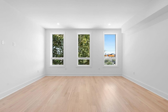 empty room with light wood-style floors, recessed lighting, a healthy amount of sunlight, and baseboards