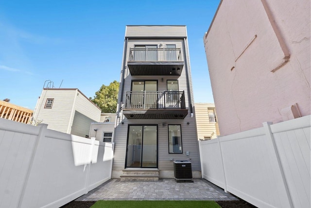 back of house with cooling unit, a fenced backyard, a balcony, and entry steps