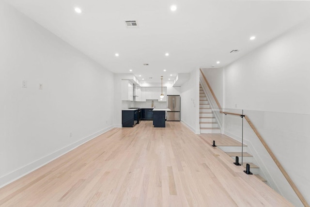 unfurnished living room featuring recessed lighting, visible vents, stairway, light wood-type flooring, and baseboards