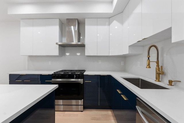 kitchen featuring wall chimney range hood, modern cabinets, white cabinetry, and stainless steel appliances