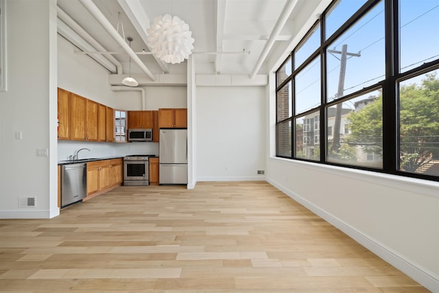 300 Communipaw Ave Unit 122, Jersey City, NJ 07304 - kitchen featuring appliances with stainless steel finishes, brown cabinetry, light wood-style flooring, a towering ceiling, and glass insert cabinets