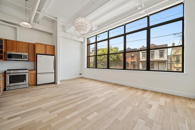 300 Communipaw Ave Unit 122, Jersey City, NJ 07304 - kitchen with stainless steel appliances, brown cabinets, light wood-type flooring, backsplash, and a chandelier