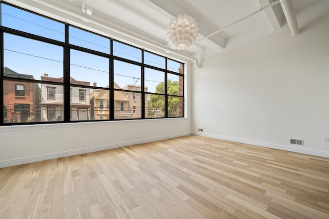 300 Communipaw Ave Unit 122, Jersey City, NJ 07304 - spare room with beam ceiling, light wood-type flooring, and a chandelier