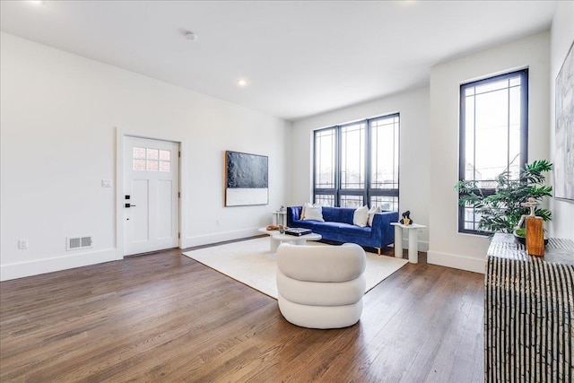 living area featuring visible vents, wood finished floors, and baseboards