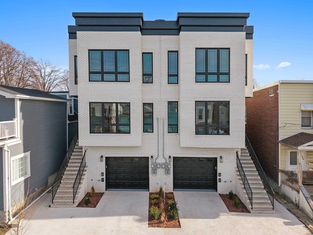 view of front facade featuring stairs, a garage, brick siding, and driveway