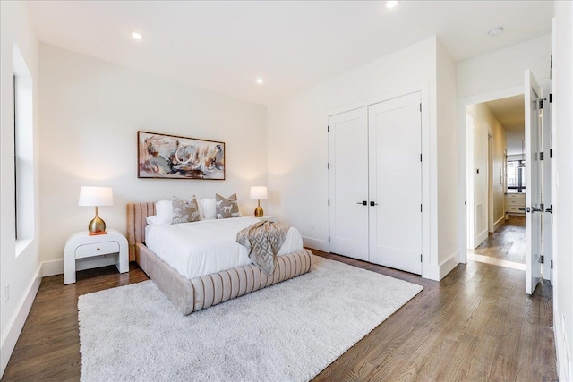 bedroom with recessed lighting, wood finished floors, baseboards, and a closet