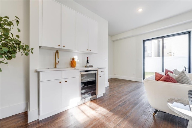 bar featuring baseboards, wine cooler, indoor wet bar, wood finished floors, and a sink