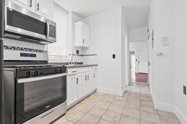 310 28th St, Union City, NJ 07087 - kitchen featuring stainless steel appliances, a sink, tasteful backsplash, light tile patterned floors, and white cabinetry