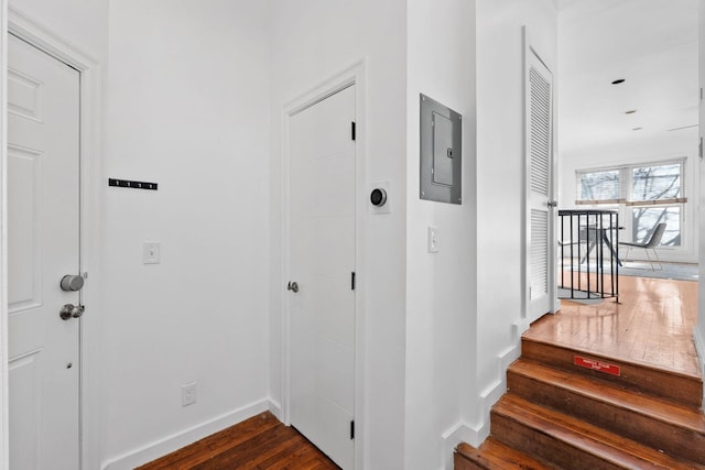 interior space featuring electric panel, baseboards, and wood finished floors