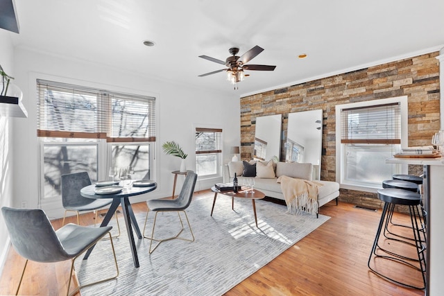 living area featuring light wood-style flooring, crown molding, ceiling fan, and visible vents