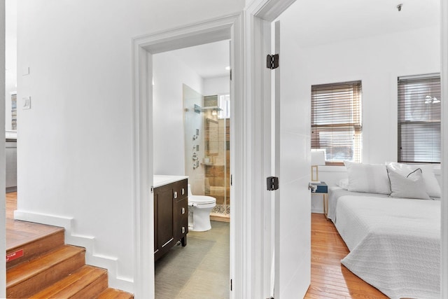 bedroom with light wood-style flooring and connected bathroom