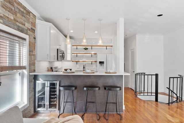 kitchen featuring tasteful backsplash, white fridge with ice dispenser, light wood-type flooring, stainless steel microwave, and beverage cooler
